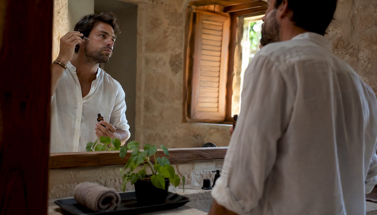 Man applying hyaluronic acid serum in bathroom