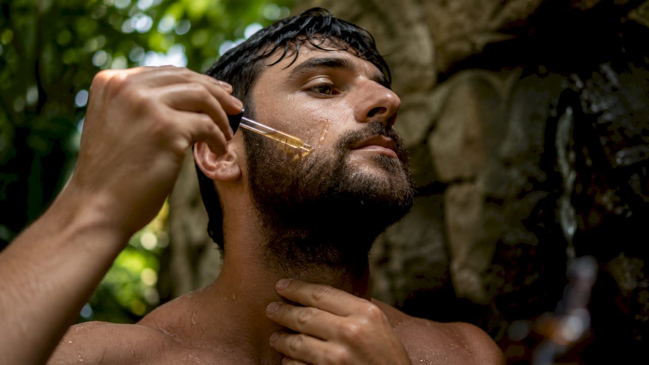 Man applying jojoba oil to beard and face