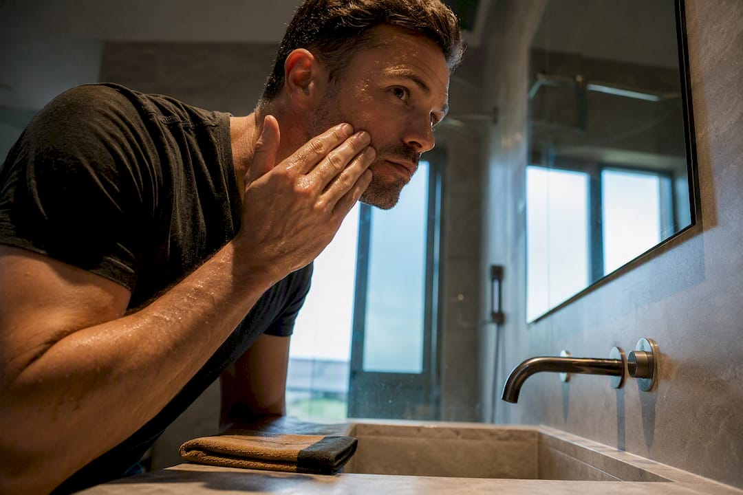 Man applying hydration to damp facial skin
