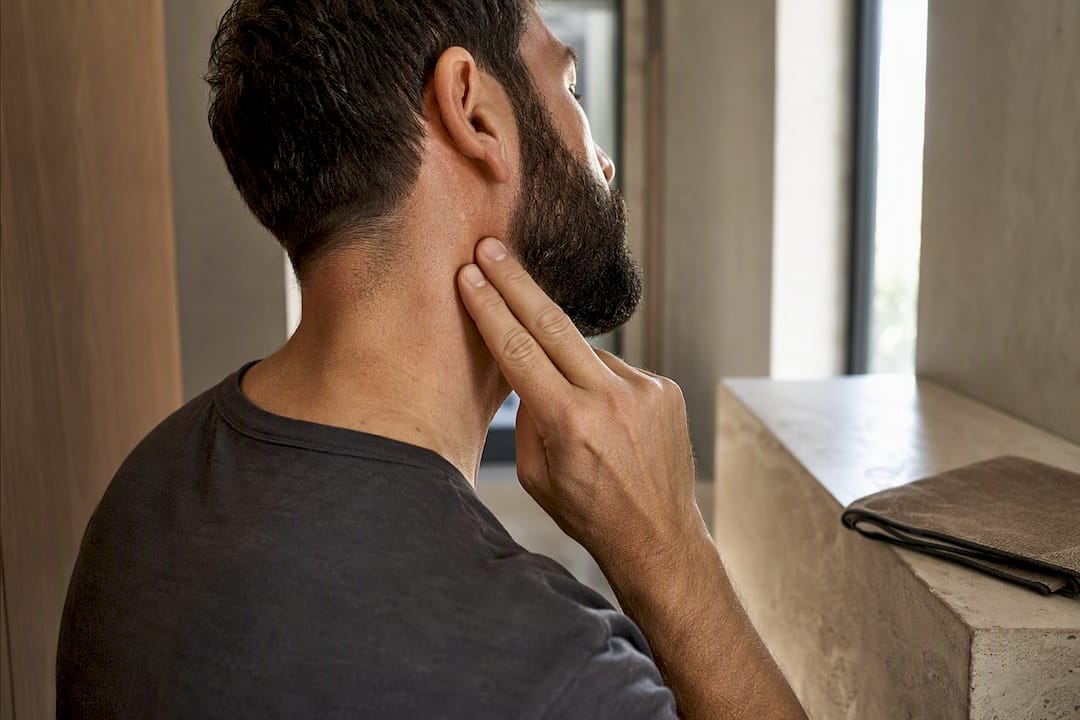 Man applying sunscreen behind ear and neck