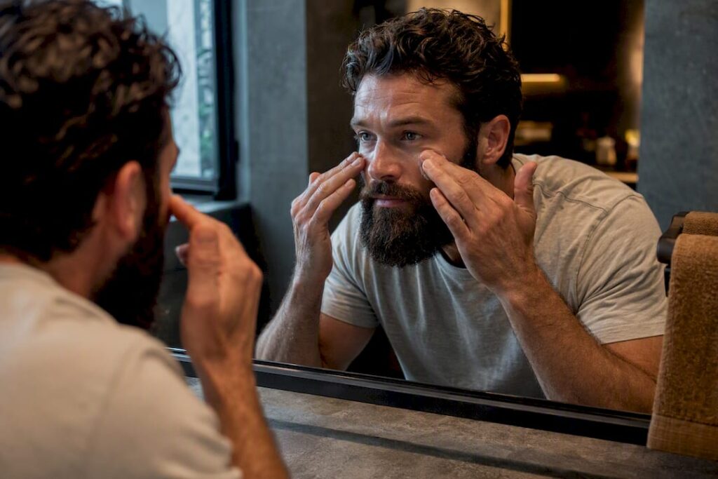 Bearded man applying sunscreen during morning routine