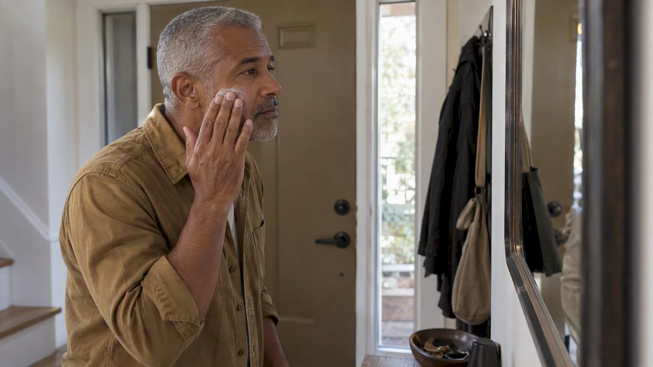 Man applying sunscreen before leaving home